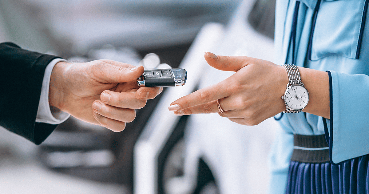 a man handing a car key to a woman - used car loan settled
